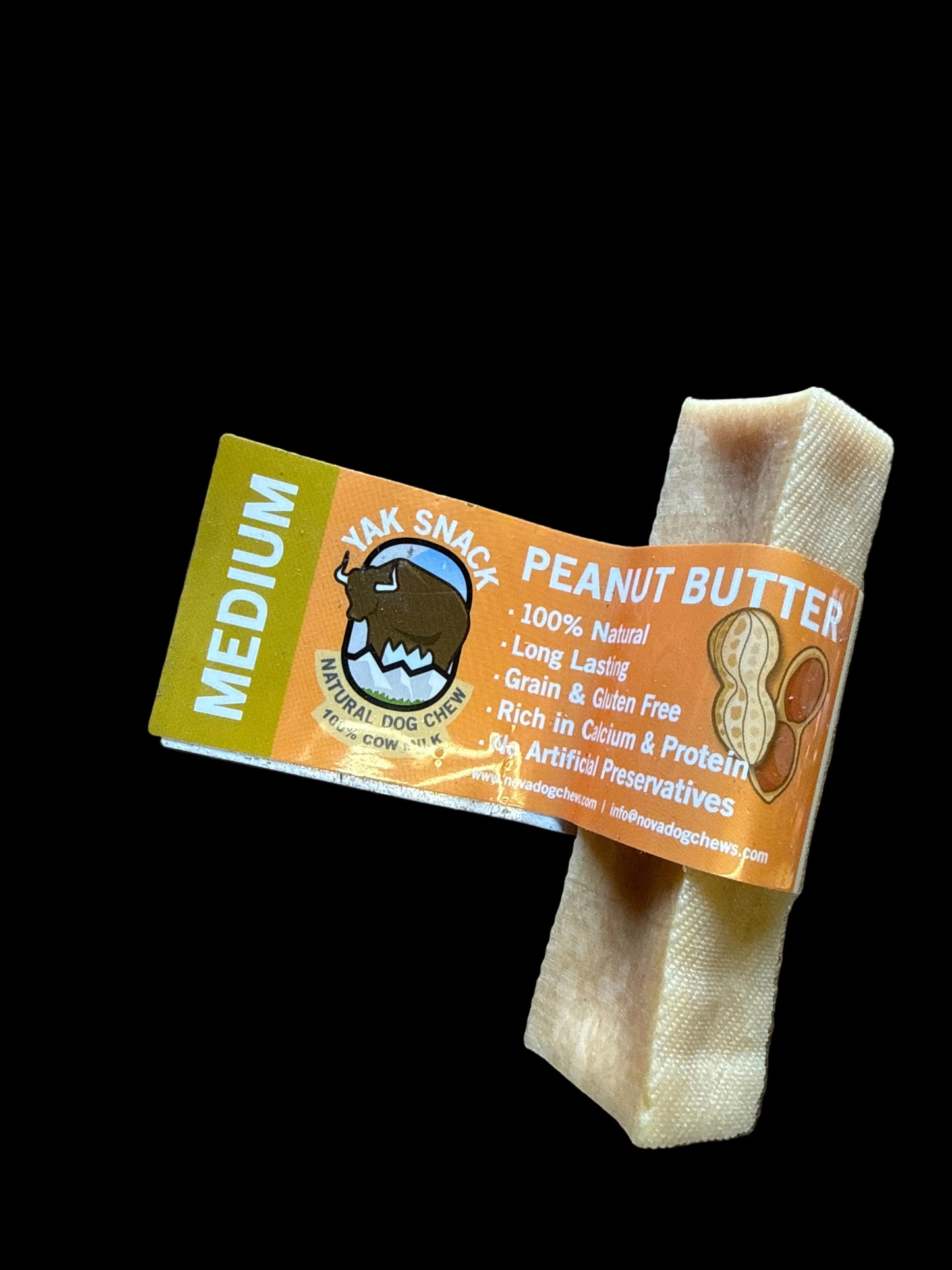 A bar of natural peanut butter soap by Snak Snack, wrapped in an orange and yellow paper label, resting on a rustic wooden surface.