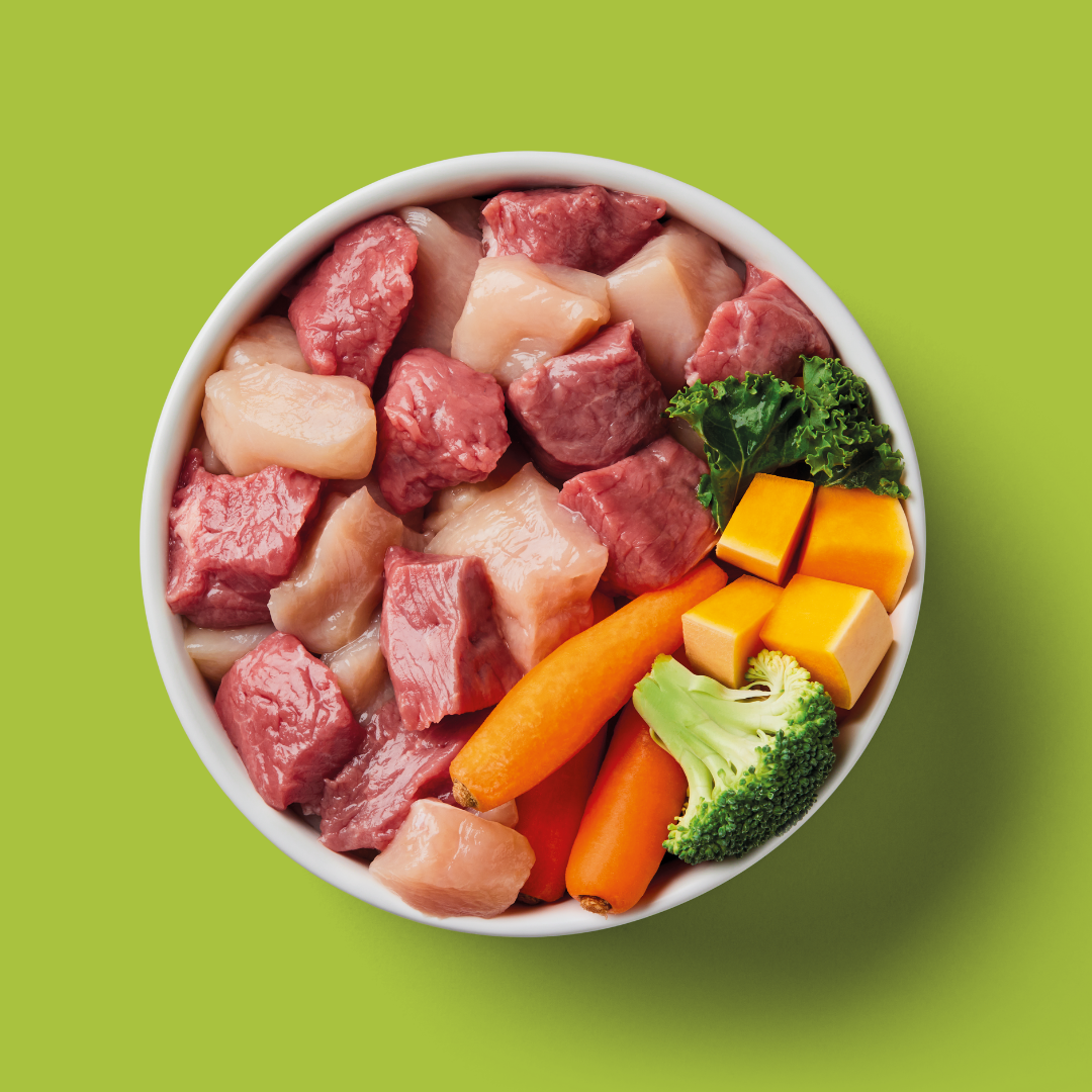 Assorted raw meat and vegetables in a white bowl on a green background