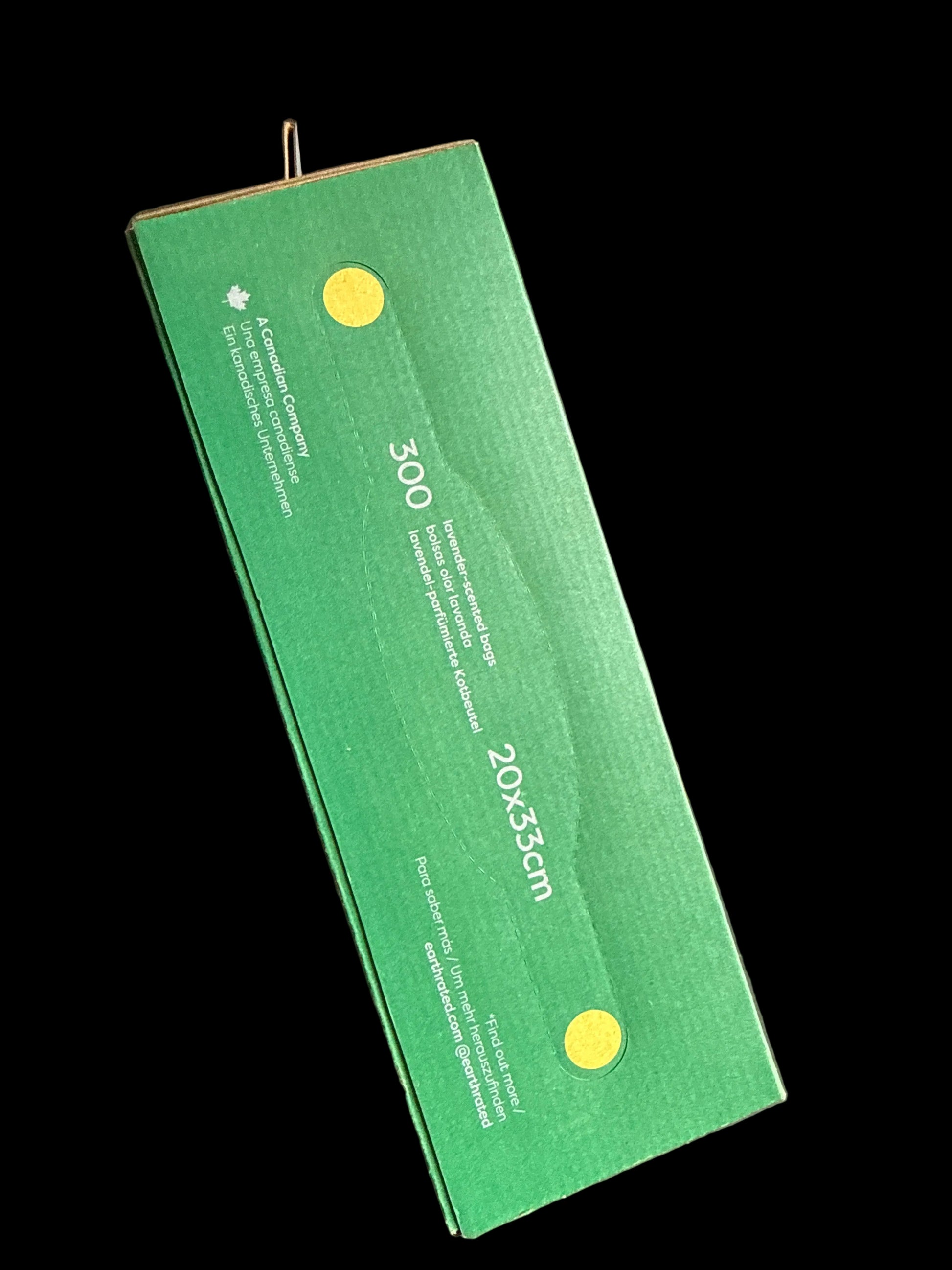 A green cardboard box of 300 vertical rolled bags, 20x33cm, photographed on a dark, worn concrete floor.