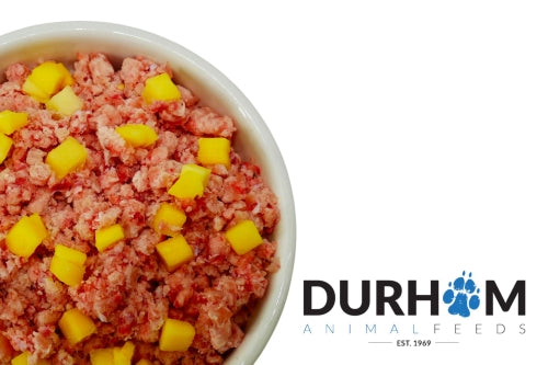 Raw chicken minced dog food with yellow mango chunks in a bowl, branded with Durham Animal Feeds.